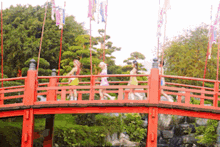 a group of people crossing a red bridge in a park