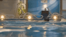 a man is swimming in a swimming pool with his shirt off .