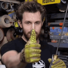 a man wearing yellow gloves and a black shirt with a boat on it holds a sword
