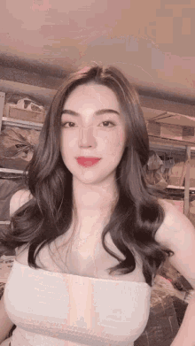 a woman with long dark hair is wearing a white top and red lipstick .