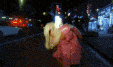 a woman in a pink jacket is walking down a street