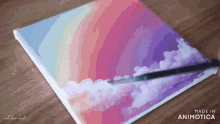 a person is painting a rainbow and clouds on a canvas