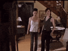 two women are standing in a living room in front of a staircase