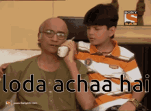 a man is talking on a phone next to a boy with the words " loda achaa hai " on the bottom