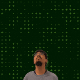 a man with glasses stands in front of a green background with the number 6 + 7 on it