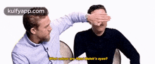 a man is covering another man 's eyes with his hand and says what colour are rami malek 's eyes .
