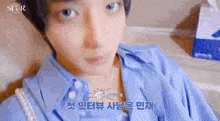 a close up of a person wearing a blue shirt and a pearl necklace .