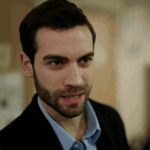 a man with a beard and a blue shirt is smiling