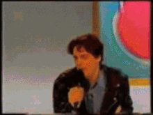 a blurry picture of a man in a black jacket talking into a microphone