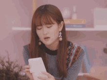 a young woman holds a white cup in her hand and looks at it