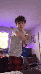 a young boy is dancing in a bedroom in front of a window .