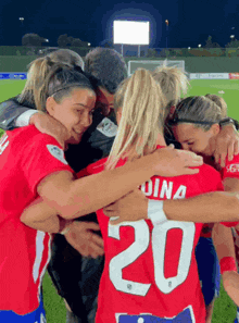 a group of female soccer players huddle together and one of them has the number 20 on her back