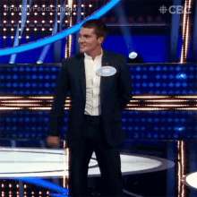 a man in a suit and white shirt is standing on a stage on a television show .