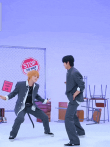 two men are dancing in front of a sign that says " stop do not enter "