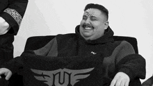 a man is sitting on a couch with a pillow that says ' snf ' on it