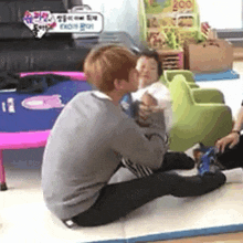 a man is sitting on the floor kissing a baby on the cheek