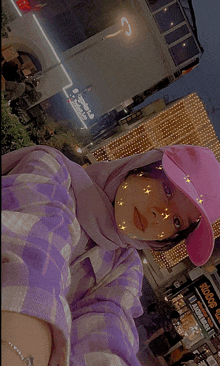 a woman wearing a pink hat is standing in front of a sign that says ' sarma ' on it
