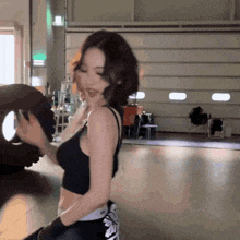 a woman in a black tank top is holding a tire in a garage