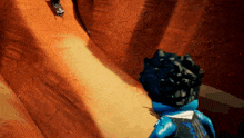 a blue lego figure is standing on a rocky hill