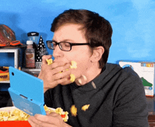 a man with glasses is eating popcorn while playing a game on a nintendo 3ds