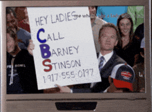 a man is holding a sign that says hey ladies call barney stinson