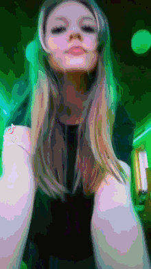 a woman with green hair is wearing headphones and has tiktok on her phone