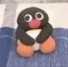 a stuffed penguin is sitting on a bed holding a piece of cheese .