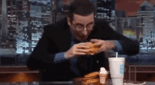 a man sitting at a table eating a burger