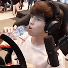 a man wearing headphones is sitting in a chair drinking water from a bottle