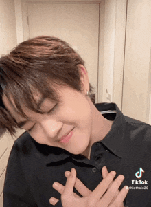 a young man with his hands on his chest has a tiktok sticker on his chest