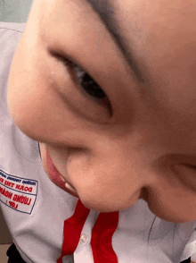 a close up of a person 's face with a patch on their shirt that says ' tnhh thao '