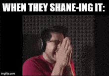 a man wearing headphones is laughing with his hands on his face .