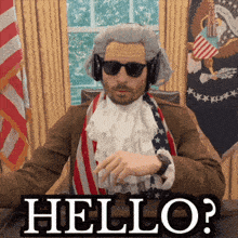 a man in a wig and sunglasses is sitting at a desk and says hello