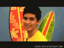 a man in a yellow shirt is smiling in front of a surfboard that says make gifs at gifsoup.com
