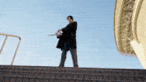 a man in a black coat is holding a sword