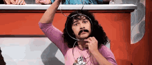a man with curly hair and a mustache is holding a wire around his neck .