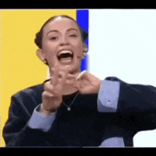 a woman is making a funny face and pointing at the camera with her fingers .