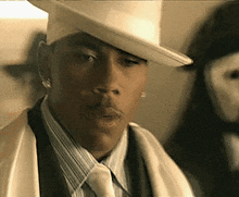 a man wearing a white hat and a white suit is looking at something .