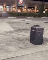 a trash can sits on the sidewalk in front of a chick-fil-a restaurant