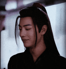 a close up of a man 's face with long hair and a ponytail