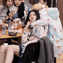 a woman sitting at a table with a can of cold water