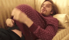 a man in a red sweater is laying on a bed holding a woman 's leg .
