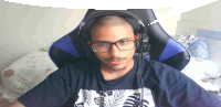 a man wearing glasses and headphones sits in a chair