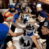 a group of men are gathered around a table with a bucket of miller lite on it