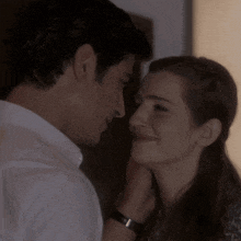 a man is touching a woman 's face and the woman is smiling