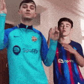 a man in a blue shirt that says spotify is standing next to another man in a blue shirt