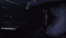 a man is sitting in a dark room with smoke coming out of the window