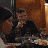 a man is eating a piece of food while sitting at a table with glasses of wine