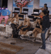 a group of women are sitting on a couch with one wearing a tank top that says ' i love you ' on it