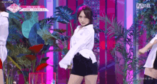 a woman in a white shirt and black shorts is dancing on a stage